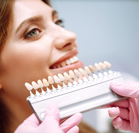 A woman with dental veneers samples in front of her teeth.